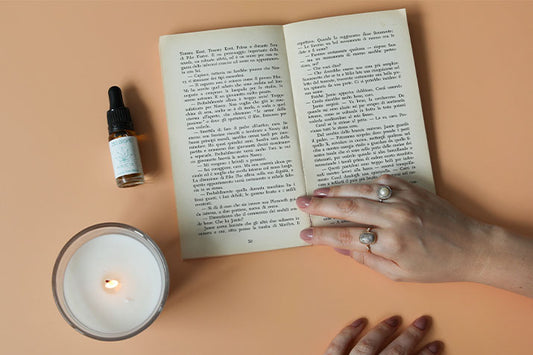 Sobre una mesa hay un libro, una vela y aceite de CBD.
