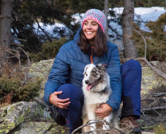 Una mujer guarda un perro en el bosque.