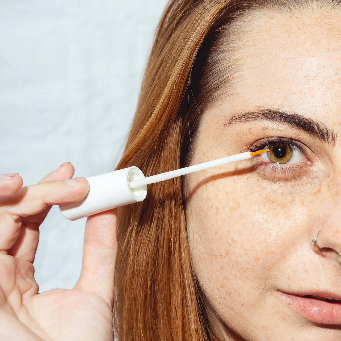 una mujer sostiene el suero delante del ojo