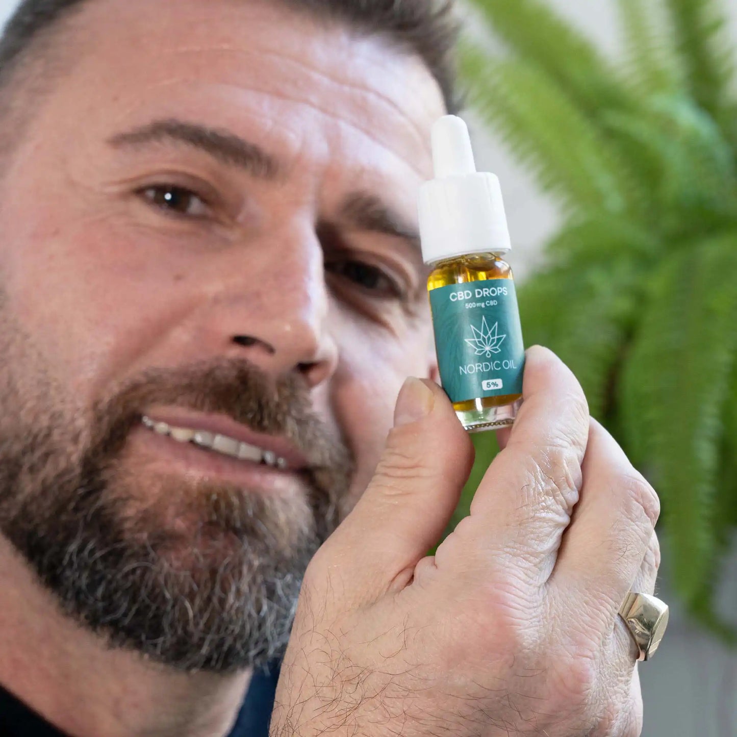 un hombre sostiene el aceite de CBD ante la cámara