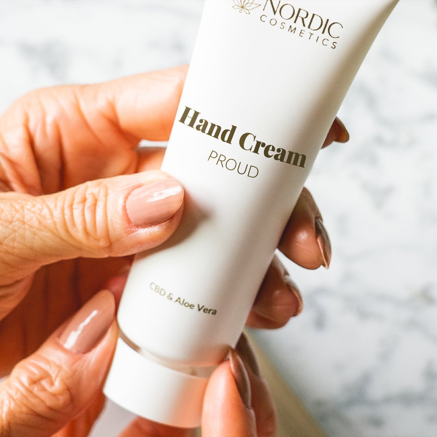 Tubo blanco de crema de manos con CBD y Aloe Vera sostenido por una mano.