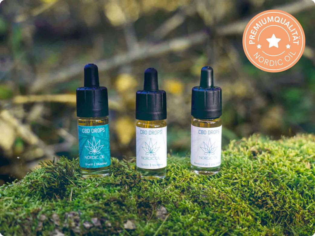 Calidad premium, tres botellas de aceite de CBD yacen sobre una piedra cubierta de musgo.