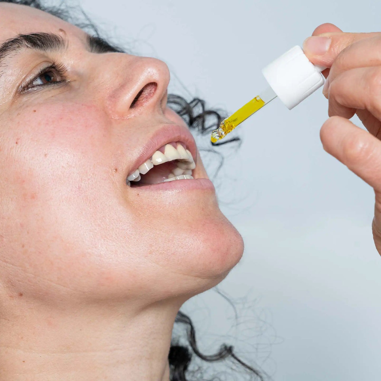 Una mujer tomando una pipeta llena de aceite de CBD de amplio espectro de Nordic Oil