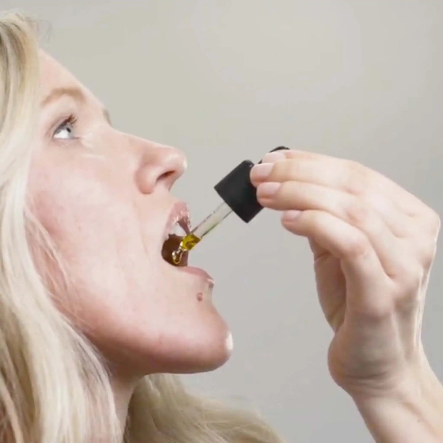 Una mujer sostiene una pipeta de aceite de CBD de amplio espectro con curcumina de Nordic Oil