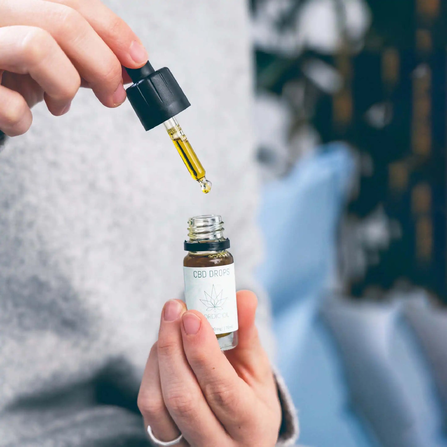 Una mujer con un frasco abierto de 10 ml de aceite de CBD de amplio espectro al 20%.