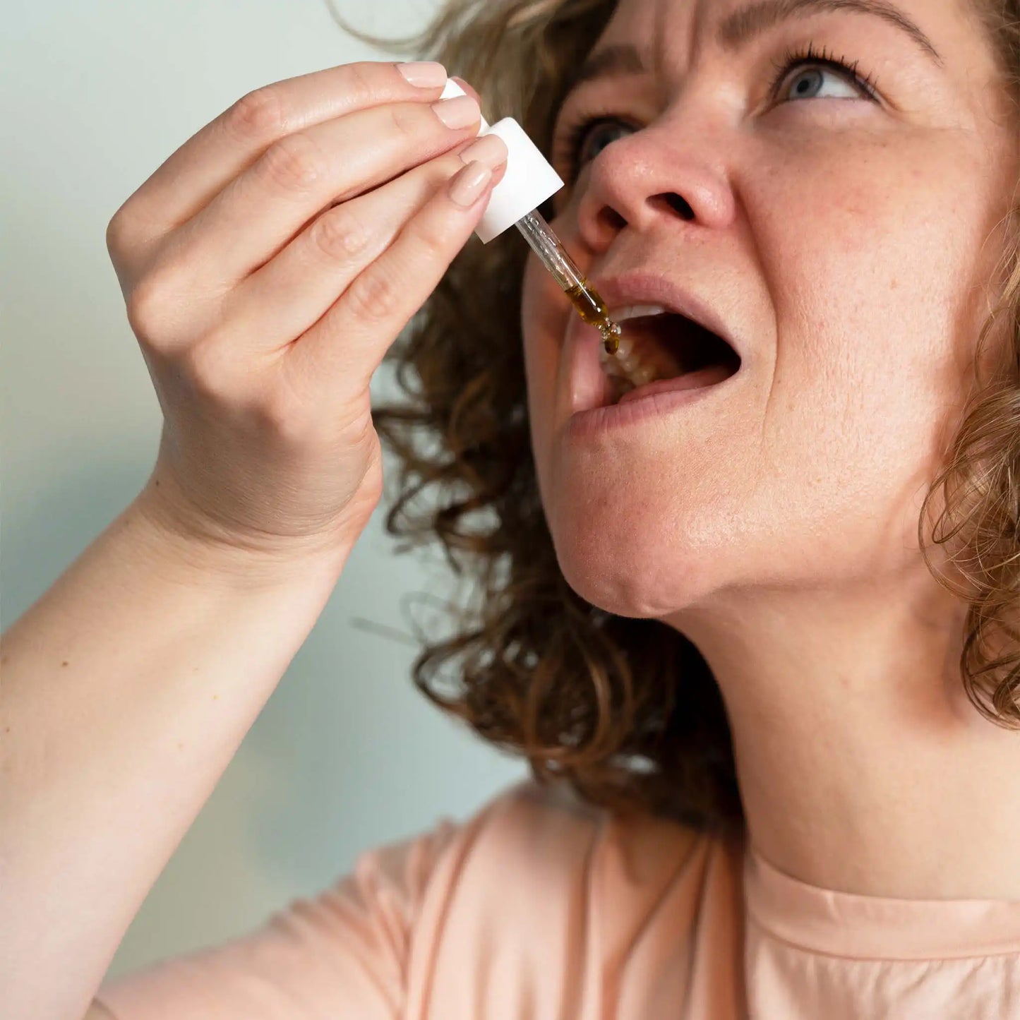 Una mujer tomando una pipeta llena de aceite de CBG de amplio espectro de Nordic Oil