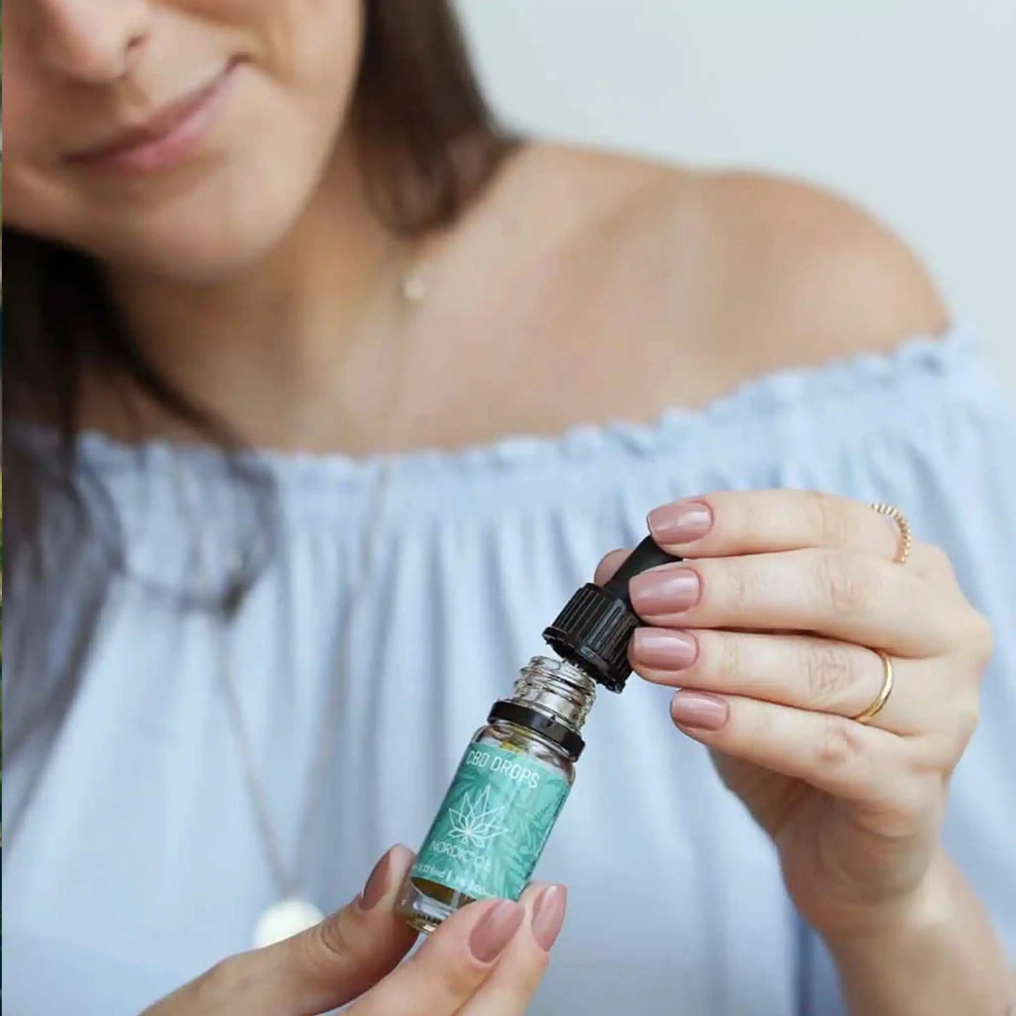 Una joven con un frasco de 10 ml de aceite de CBD de amplio espectro al 5%.