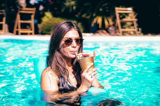 Chica en piscina con bebida fría