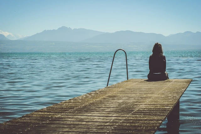 Una mujer sola mirando un lago.