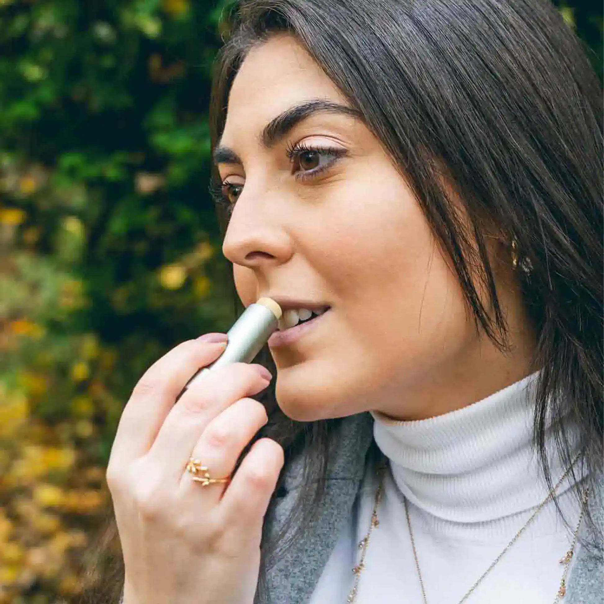 Una mujer se aplica Bálsamo labial de CBD en los labios.