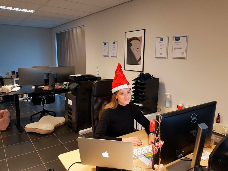 Una mujer está sentada en una oficina con un gorro navideño.