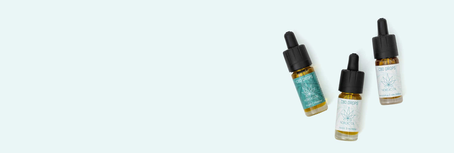 Tres botellas de aceite de CBD yacen sobre un fondo verde.