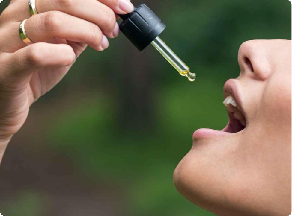 Una mujer se echa aceite de CBD en la boca