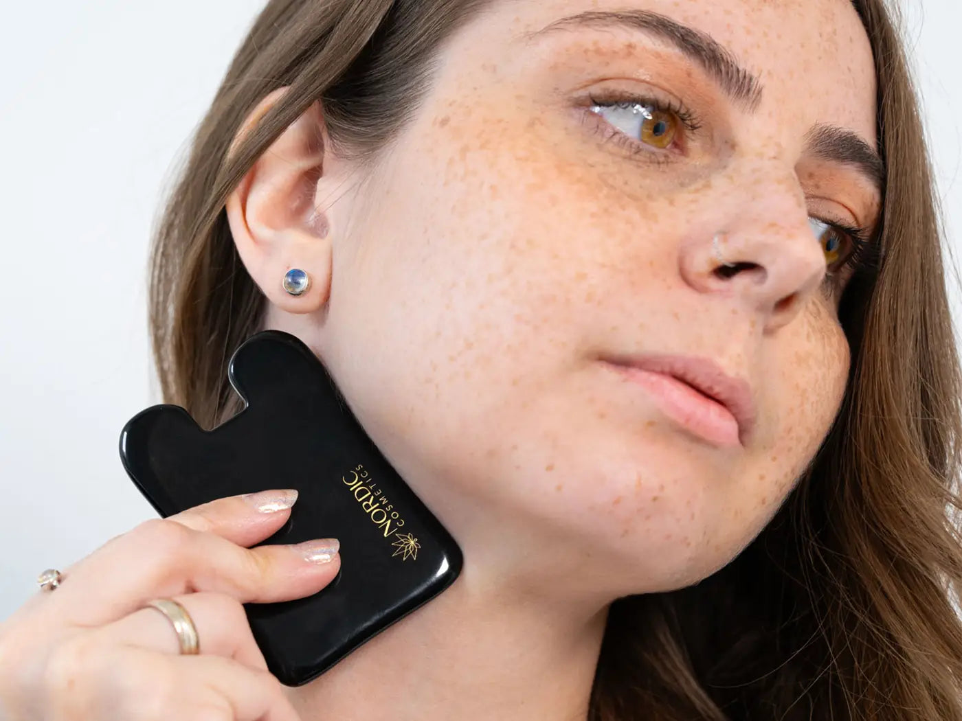 una mujer utiliza el gua sha de nordic cosmetics 