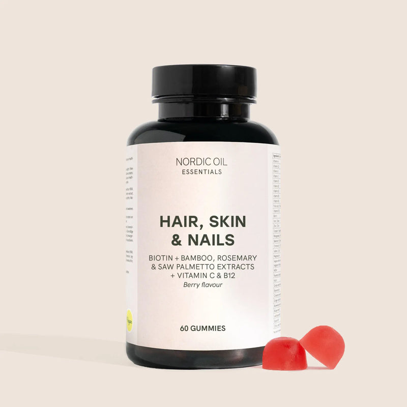 Botella de Nordic Oil Essentials Hair, Skin & Nails con dos gomitas rojas a un lado