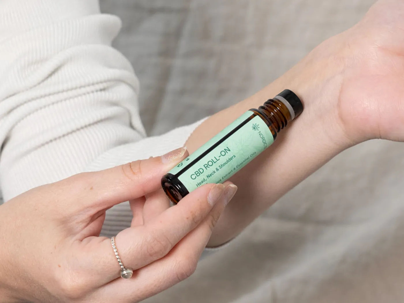 una mujer utiliza el cbd roll on de nordic oil