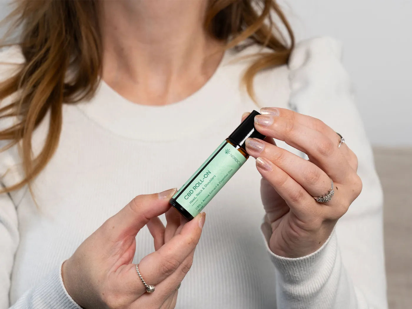 una mujer sostiene el cbd roll on de nordic oil 