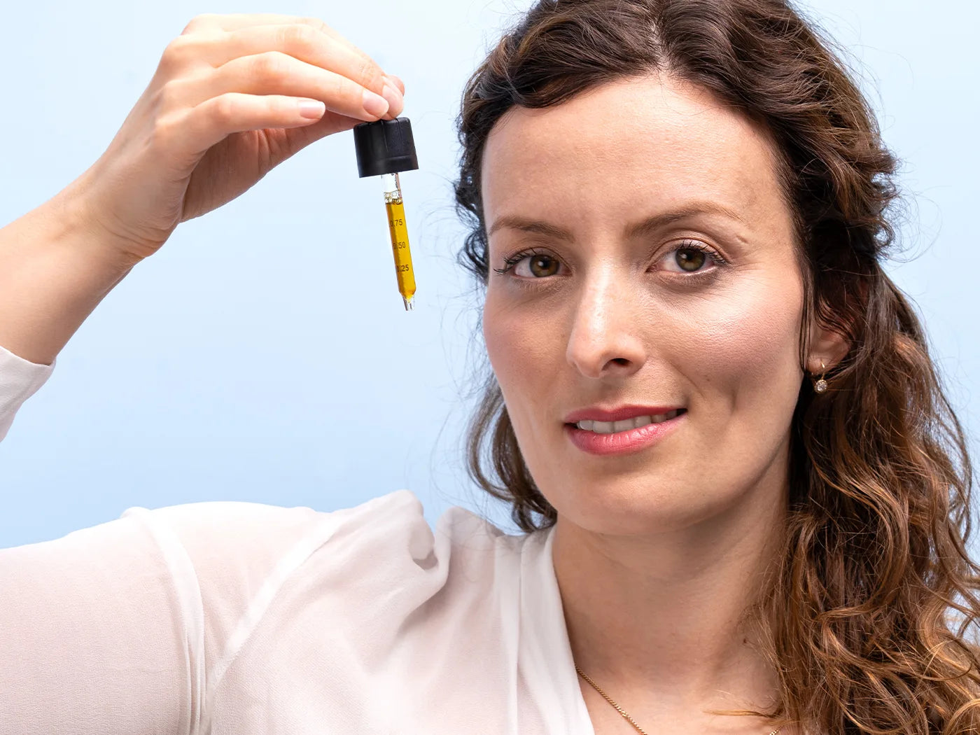 Mujer sosteniendo un gotero de aceite de CBD frente a la cara
