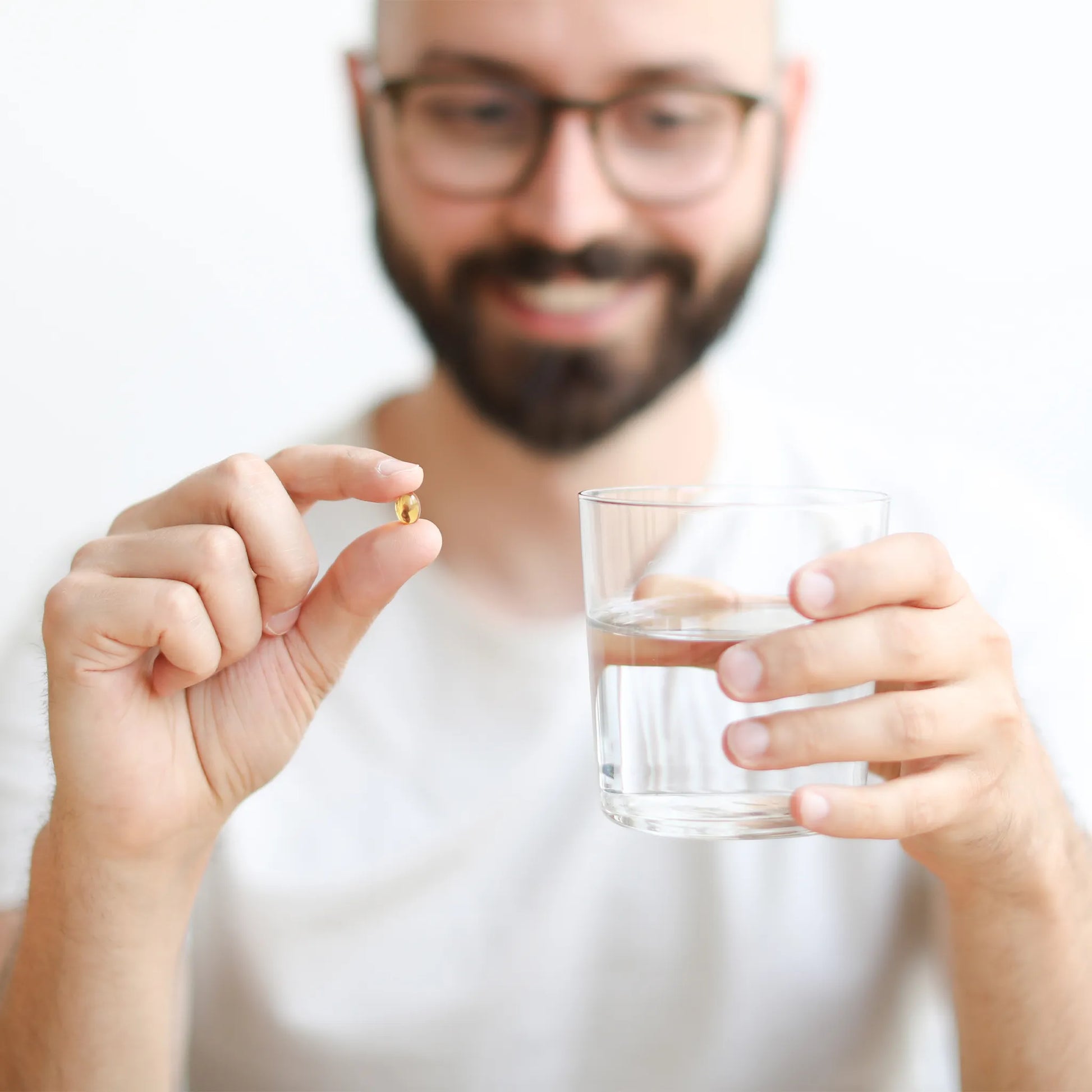 un hombre sostiene una softgel y una botella de agua