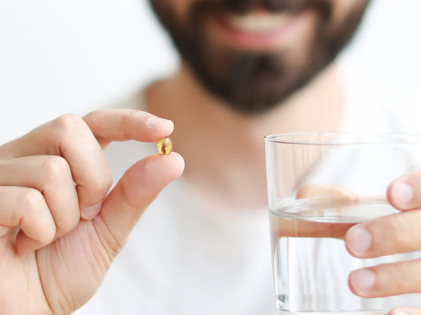 un hombre sostiene una softgel y una botella de agua 