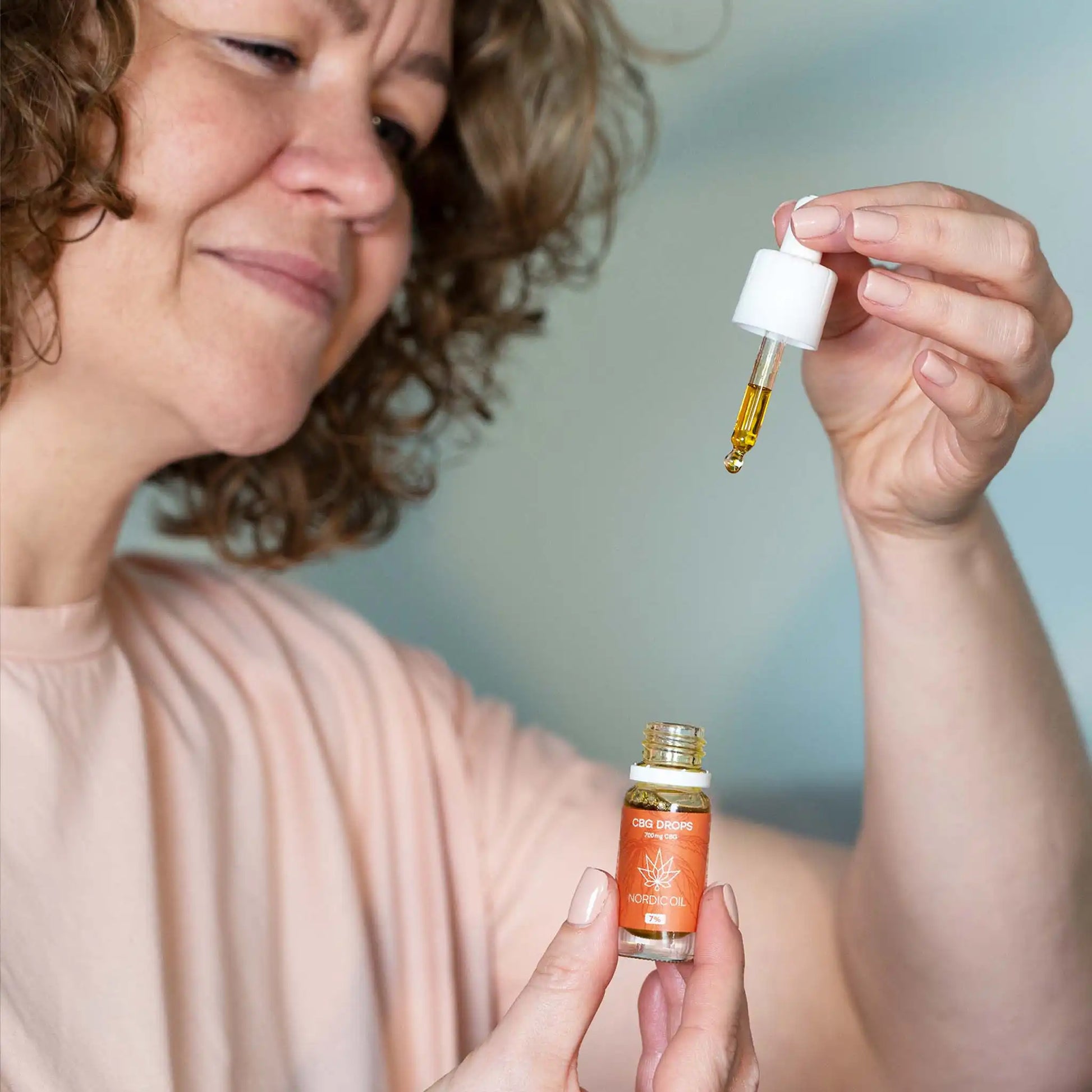 Una mujer sosteniendo un frasco abierto de 10 ml de aceite de CBG 7% de amplio espectro