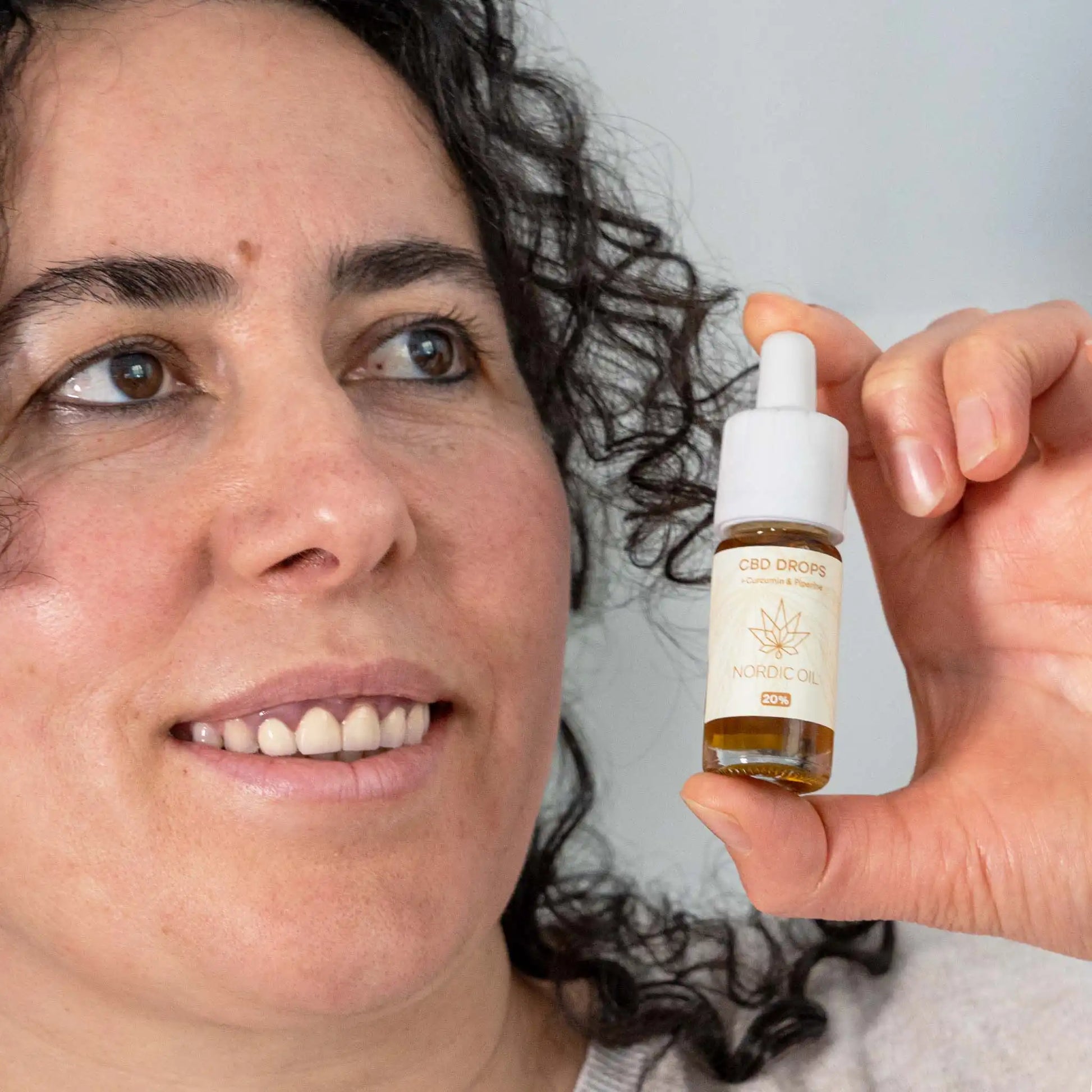 Una mujer sosteniendo una botella de aceite de CBD 12% de amplio espectro con curcumina 