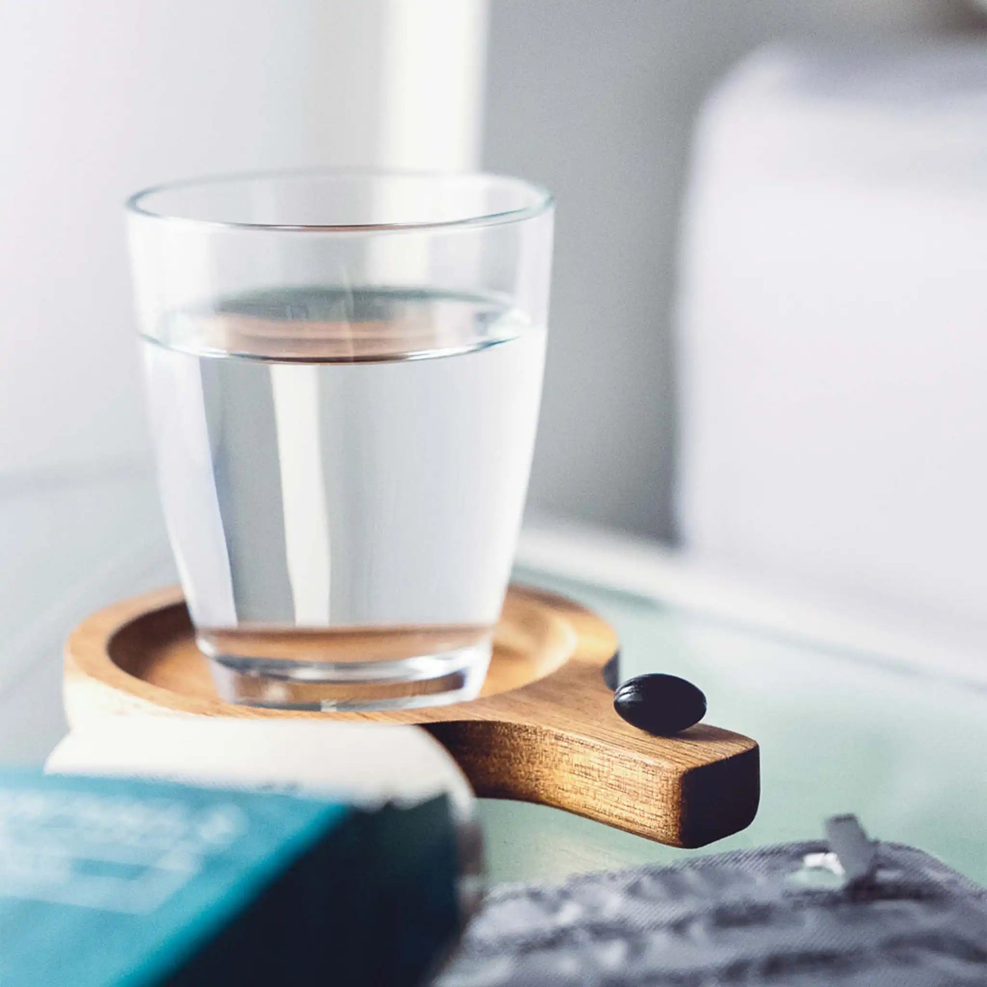 vaso de agua con una cápsula blanda al lado